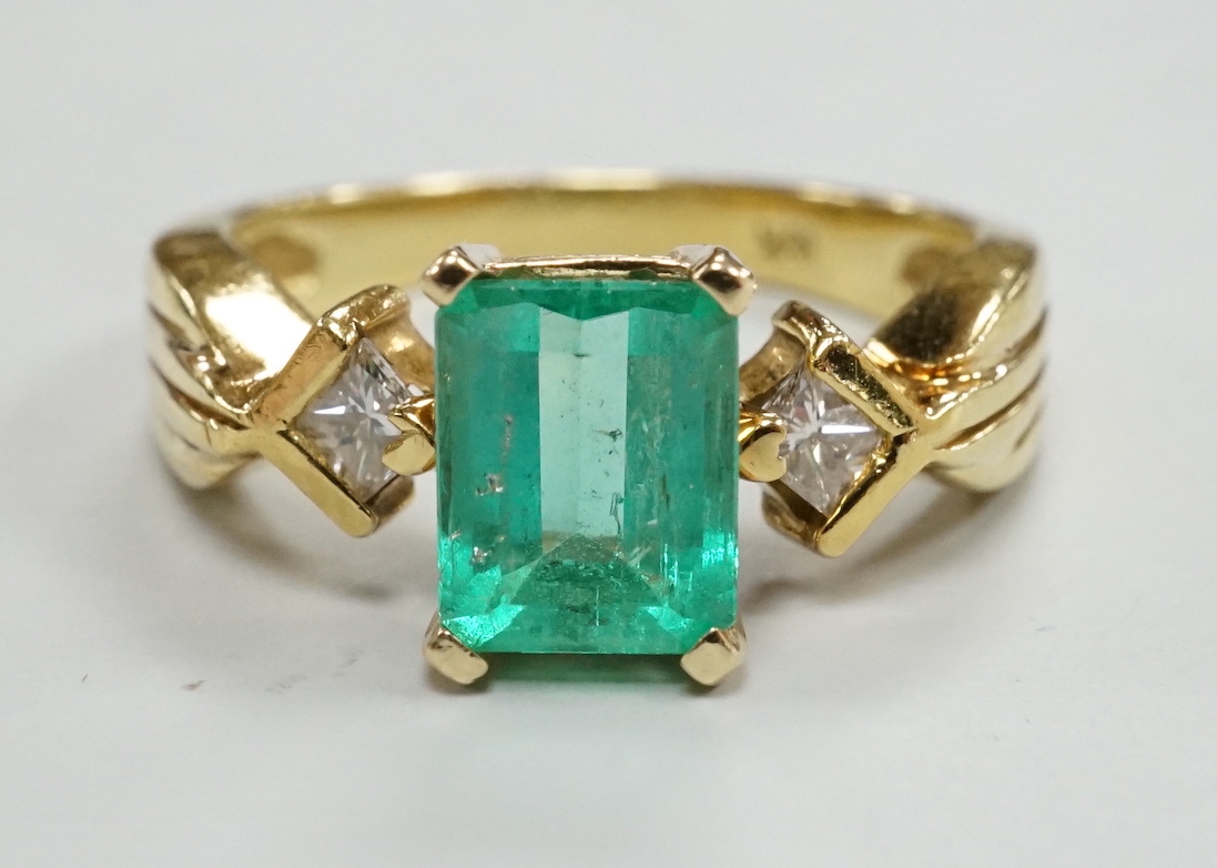 A modern 18k yellow metal and single stone emerald set ring, with two stone diamond set shoulders, size O, gross weight 5.8 grams.